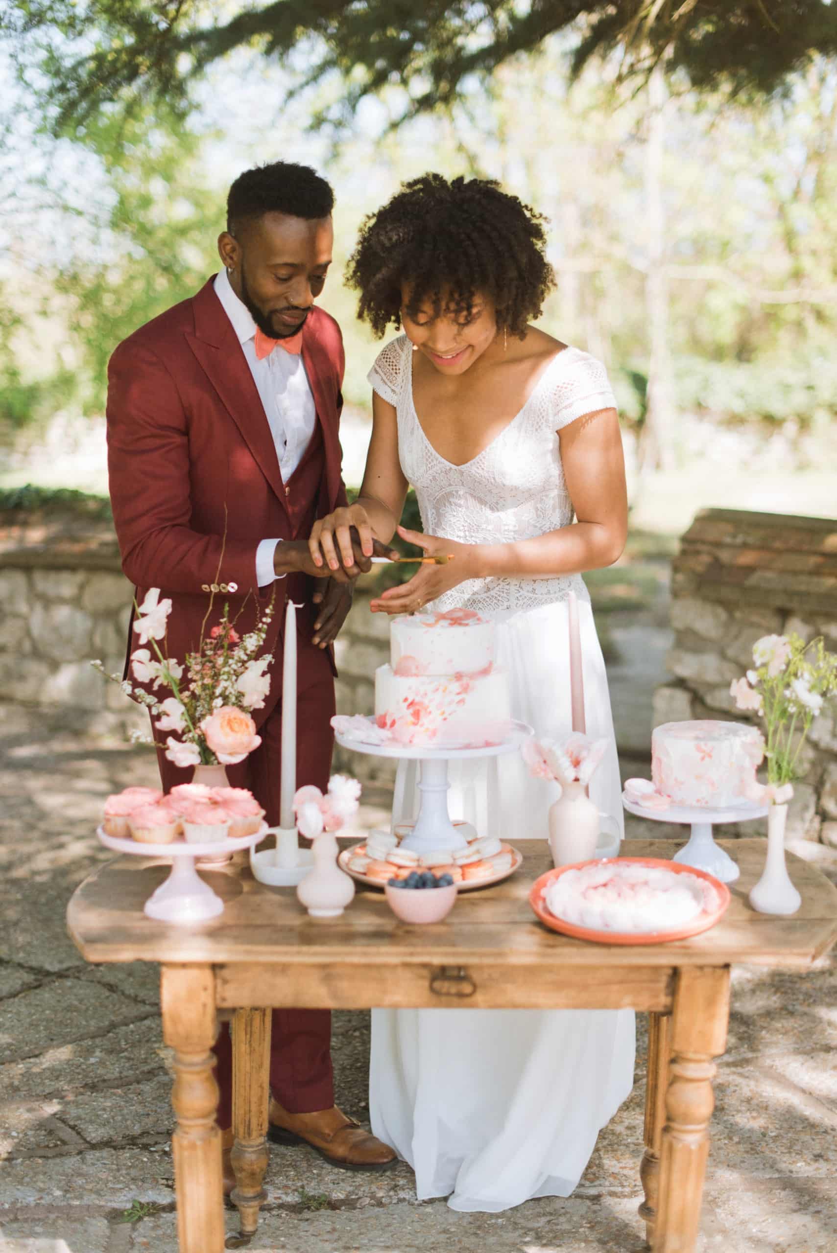couple de mariés découpant son gâteau de mariage dans un jardin