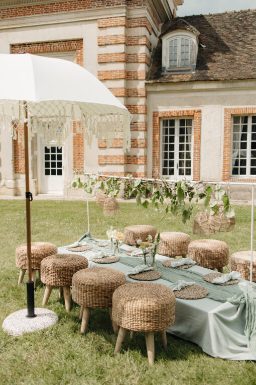 Location de mobilier pour cocktail mariage vert sauge avec un table, 8 petits tabourets et un parasol dans un thème vert sauge